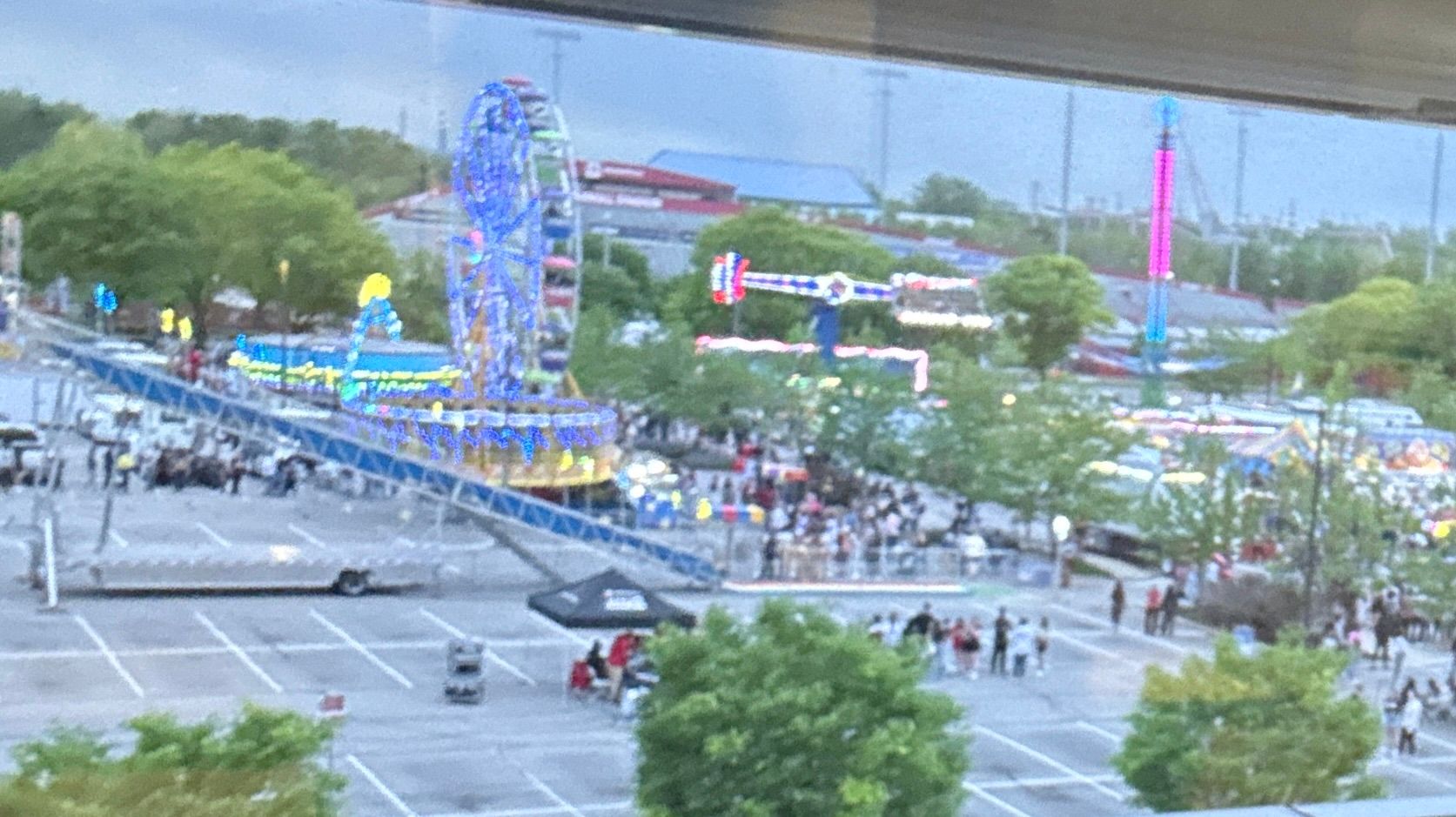 Some carnival rides outside with lots of people.